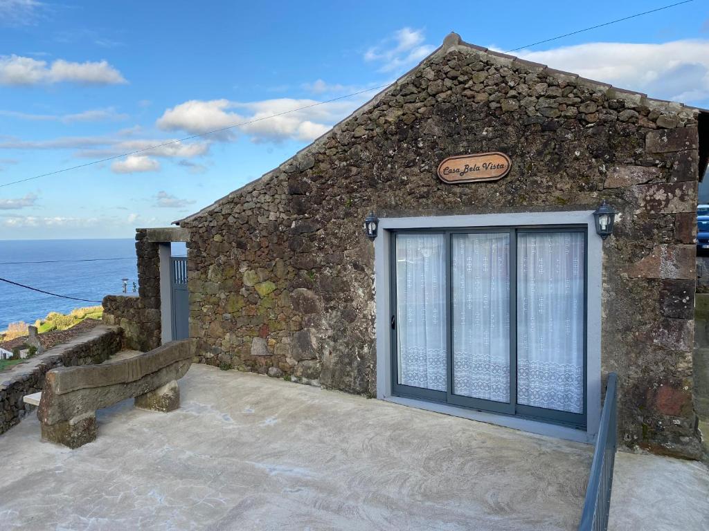 une porte menant à un bâtiment en pierre avec l'océan derrière lui dans l'établissement Casa Bela Vista, à Ponta Delgada