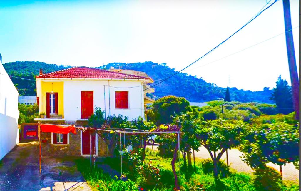 una piccola casa gialla e rossa in un giardino di TWO-BEDROOMS in GREEK VINTAGE HOME with shared Bathroom a Korinthos