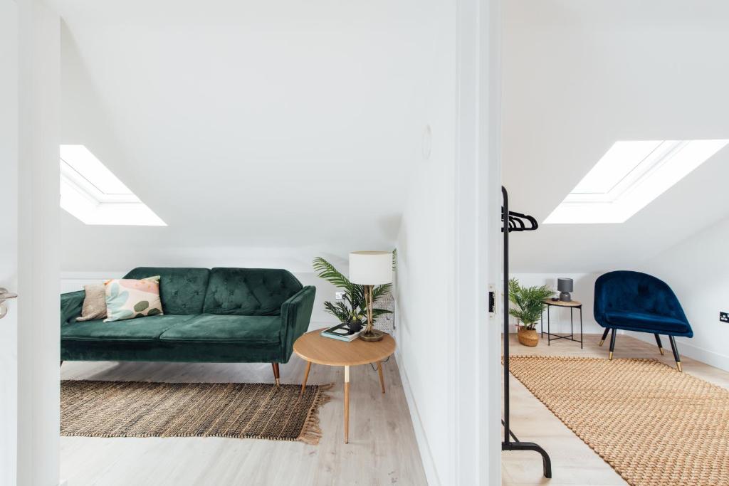 a living room with a green couch and a blue chair at Contemporary 1 Bedroom Loft in Ilford, London in Ilford