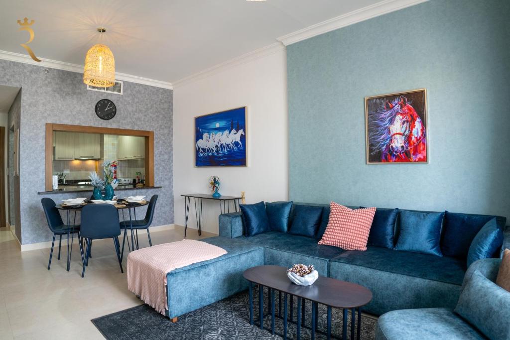 un soggiorno con divano blu e tavolo di Your 1BR Retreat on Yas Island Blue Sapphire Apartment a Abu Dhabi