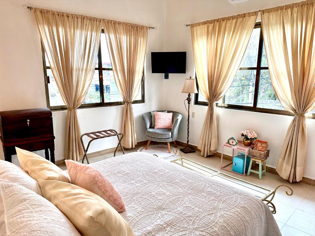 - une chambre avec un lit, une chaise et des fenêtres dans l'établissement Freijoó Casa Vintage, à Papantla