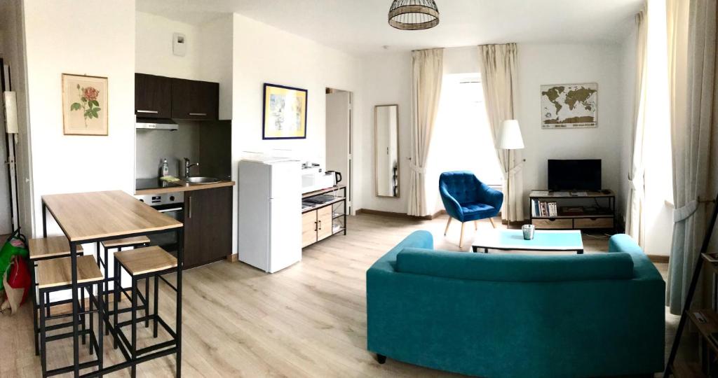 een woonkamer met een blauwe bank en een keuken bij Appartement très lumineux avec belle vue dégagée in Rochefort-en-Terre