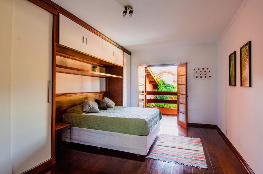um quarto com uma cama e uma porta para uma varanda em Refúgio com piscina e churrasqueira em São Paulo
