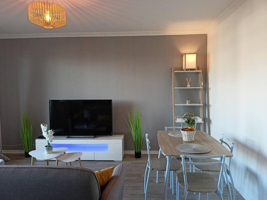 uma sala de estar com uma mesa e uma televisão em Cosy appartement avec vue sur Genève em Collonges-sous-Salève