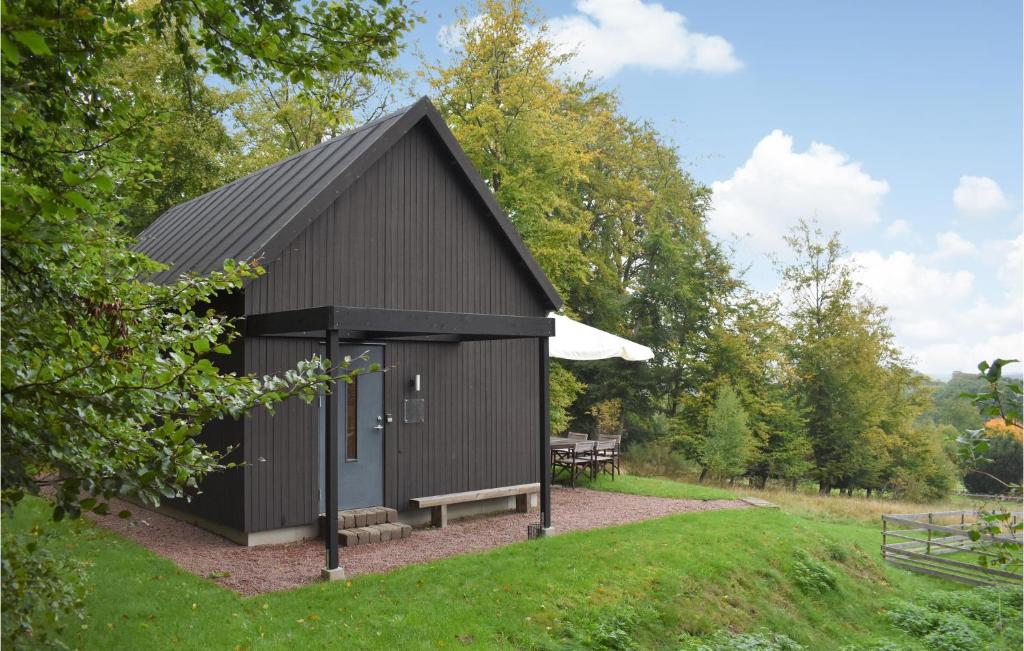 a black shed with a bench in a park at Lovely Home In stra Snnarslv With Kitchen in Östra Sönnarslöv
