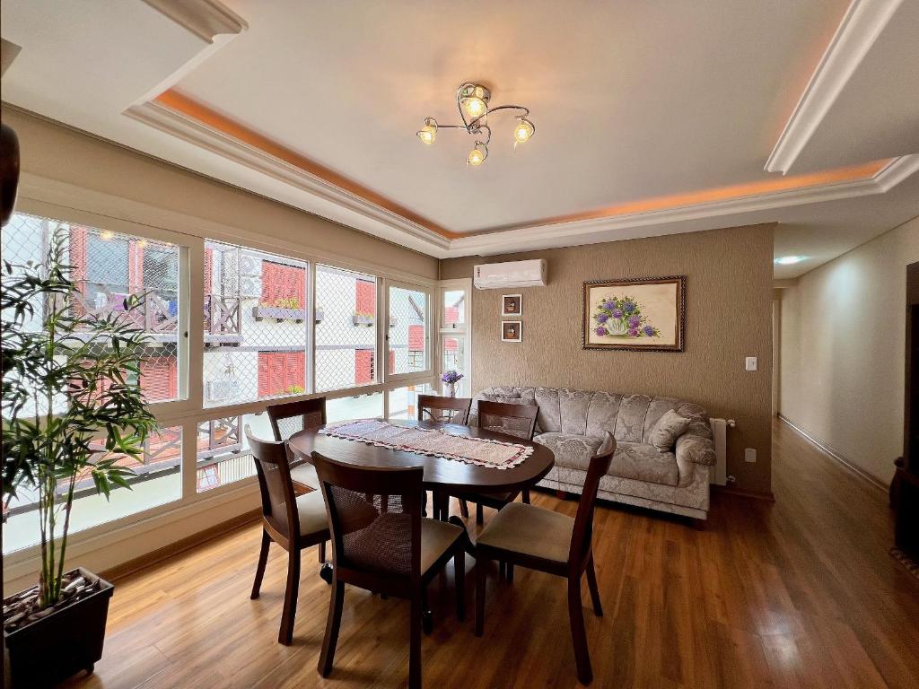 グラマドにあるApto 2dorm 500m Rua Coberta by Achei Gramadoのテーブルと椅子とソファのあるリビングルーム