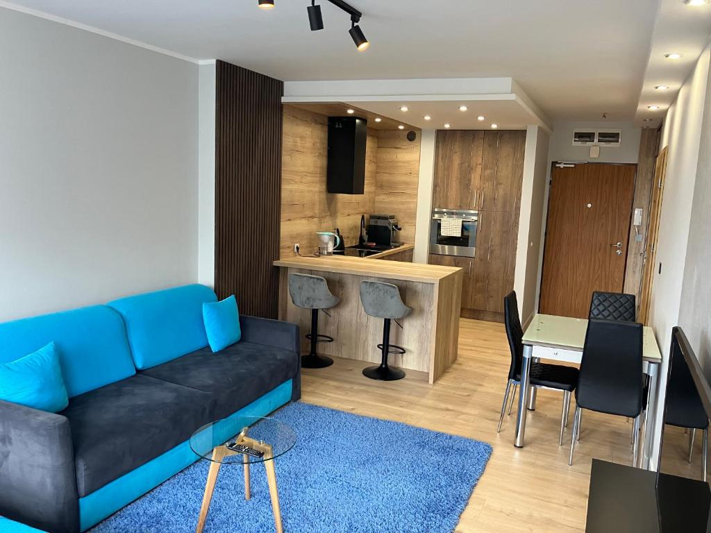 シュチェチンにあるJAB Apartments Bandurskiego Business & Familyのリビングルーム(青いソファ、テーブル付)