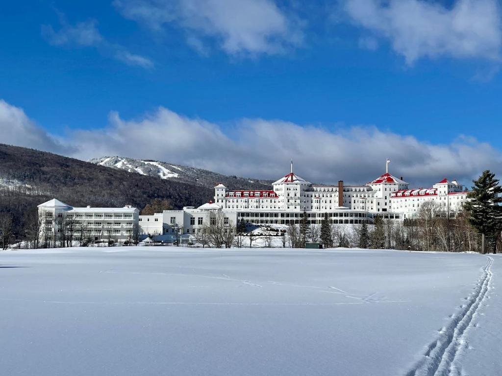 a large white building with red roofs in the snow at Omni Mount Washington Resort in Bretton Woods