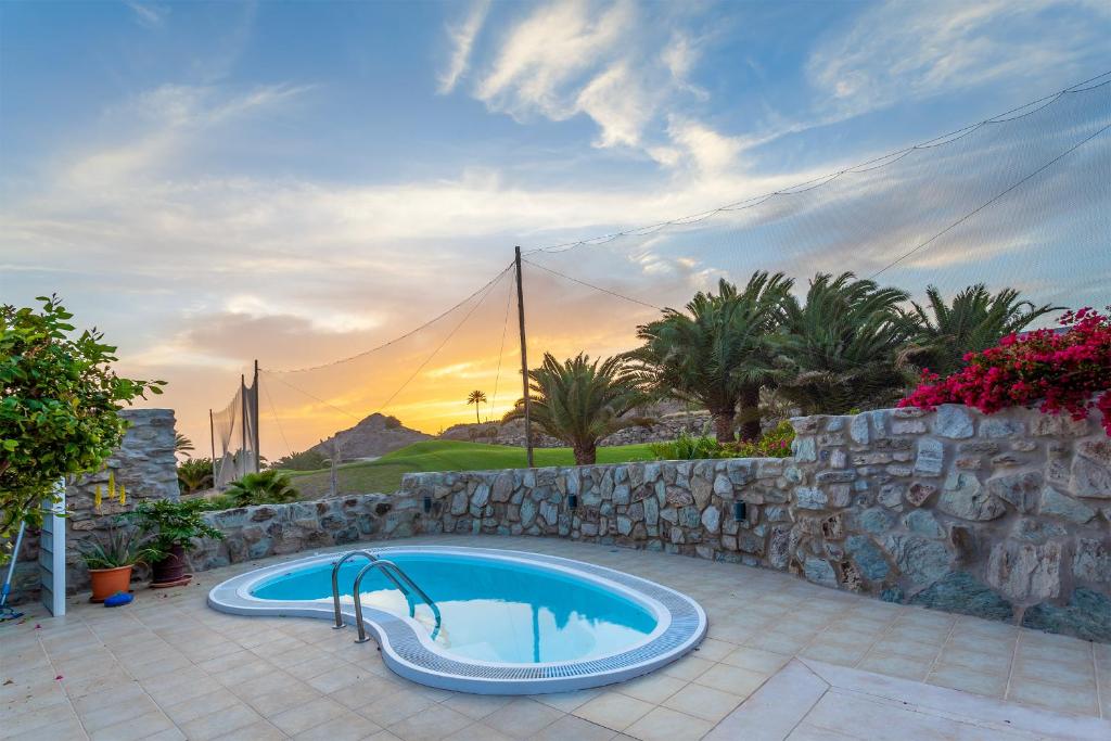 a swimming pool with a stone retaining wall and a stone wall at Zen Villa Anfi Tauro Golf Meer Pool in Mogán