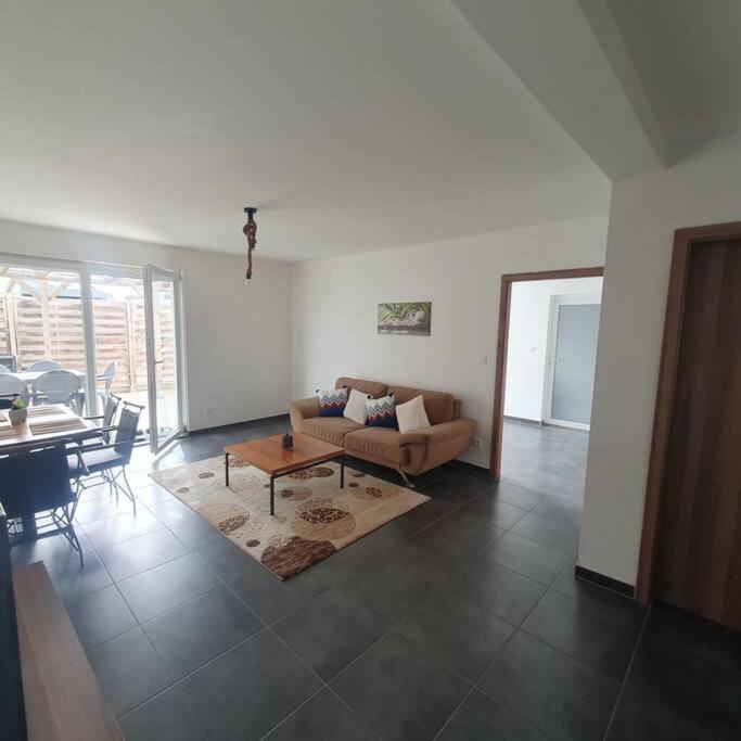 a living room with a couch and a table at Bel appartement rez de jardin in Horbourg