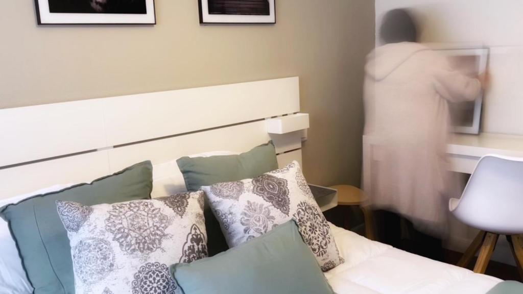 une personne debout dans une pièce avec un lit et des oreillers dans l'établissement Bilbao Matiko Tranquility near the Old town, à Bilbao