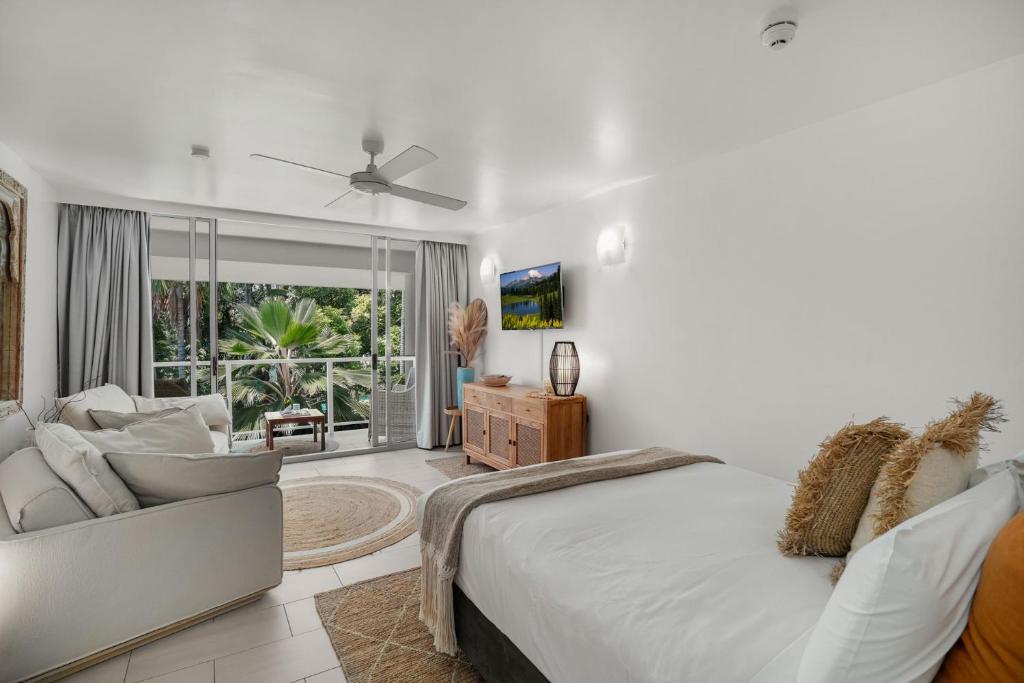 a white bedroom with a bed and a couch at Belle Escapes Drift Beachfront Resort Suite 3409 in Palm Cove