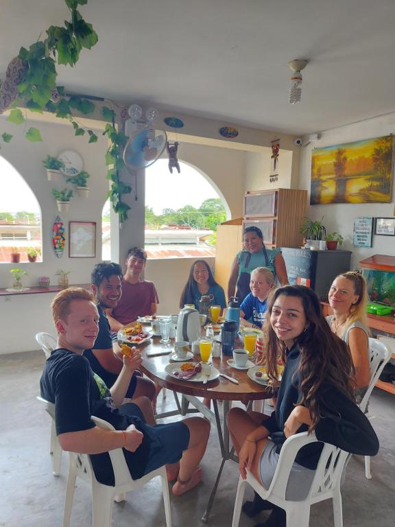 een groep mensen die rond een tafel zitten bij Amazon House Hostel in Iquitos