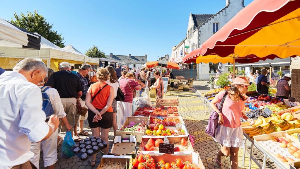 a group of people standing around a market with fruits and vegetables at Villa Saint Kirio - piscine et spa in Morlaix