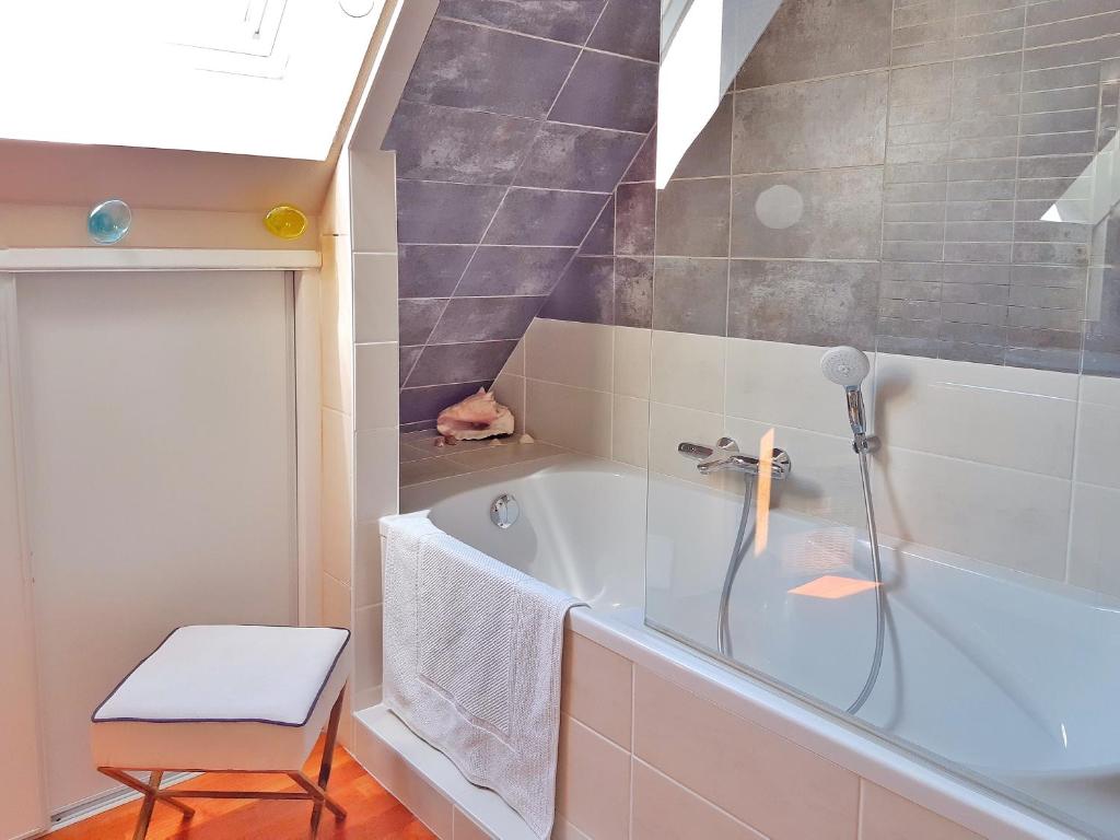 a bathroom with a bath tub and a chair at Villa Saint Kirio - piscine et spa in Morlaix