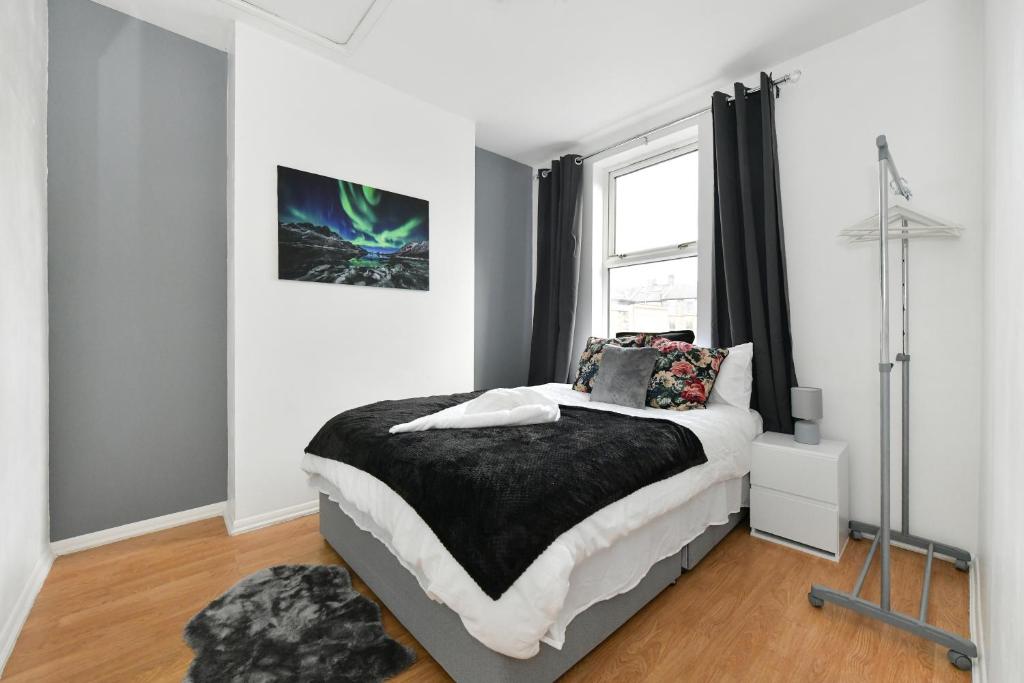a bedroom with a bed and a window at Comfy 4 bed house close to station and theatre in London