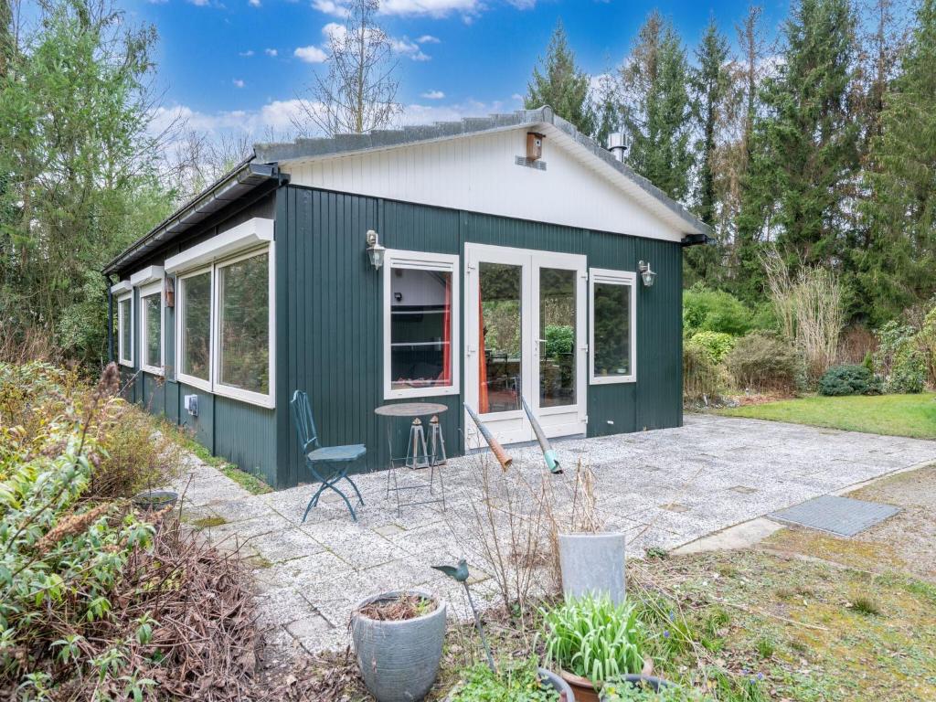 a green and white tiny house with a patio at Beautiful holiday home in Arendonk with garden in Arendonk