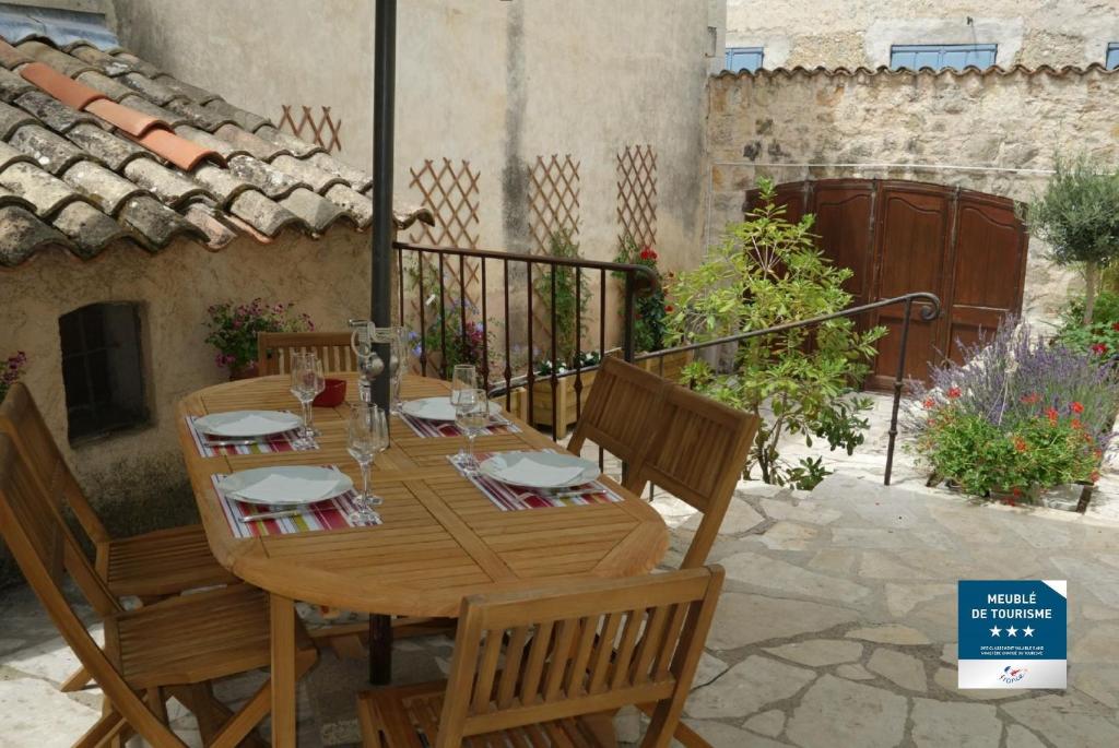 einen Holztisch und Stühle auf einer Terrasse in der Unterkunft Le Jardin du Village - Valbonne in Valbonne