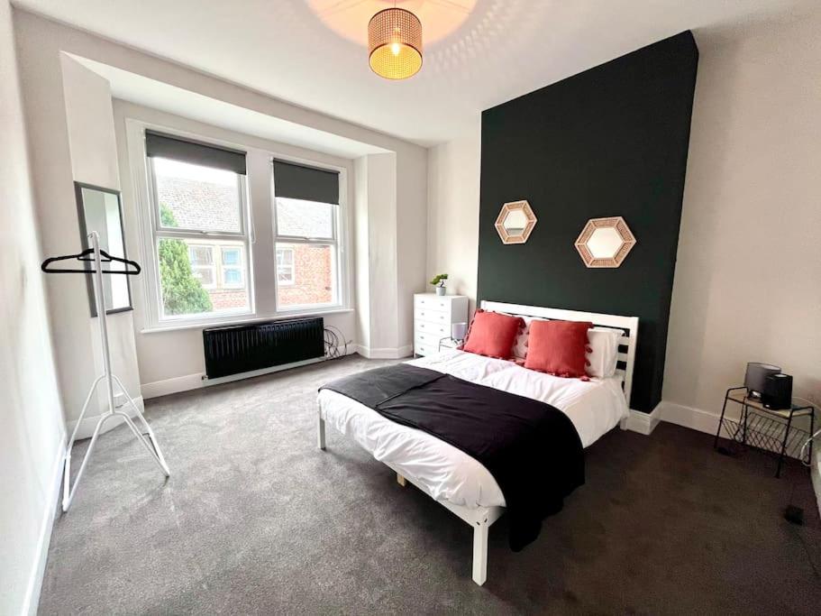 a bedroom with a large bed with red pillows at 4 bedroom home 10 mins to city in Gateshead