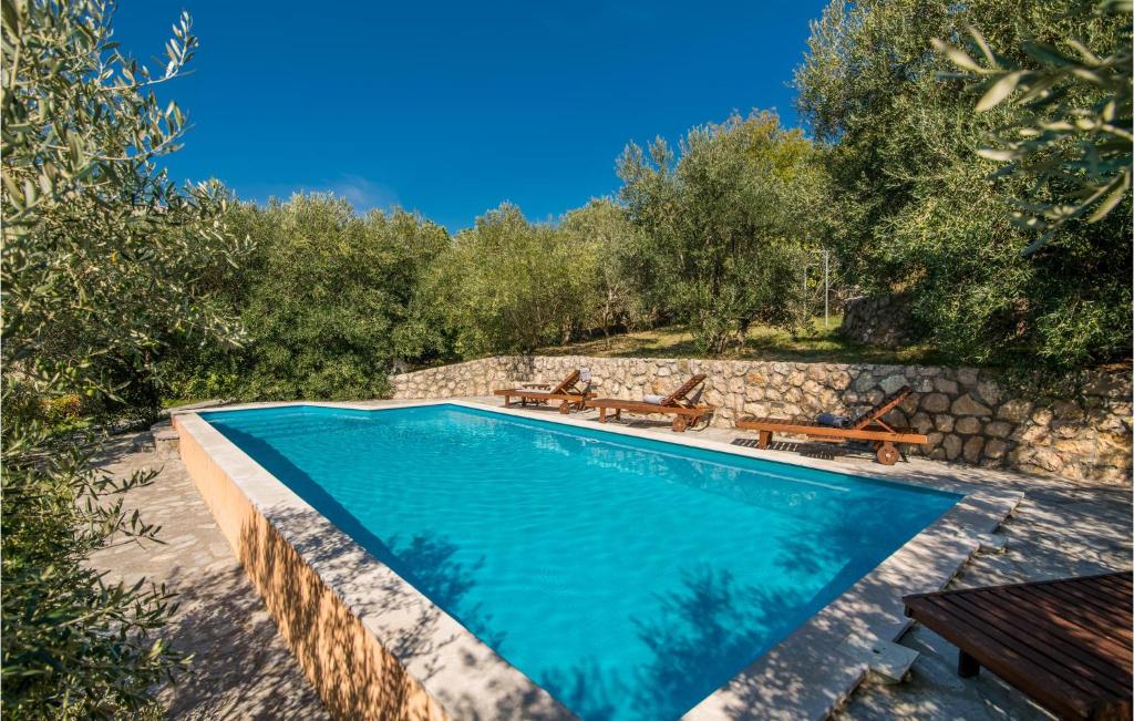 a swimming pool in a garden with benches and trees at Amazing Home In Draga Bascanska With Outdoor Swimming Pool in Draga Bašćanska