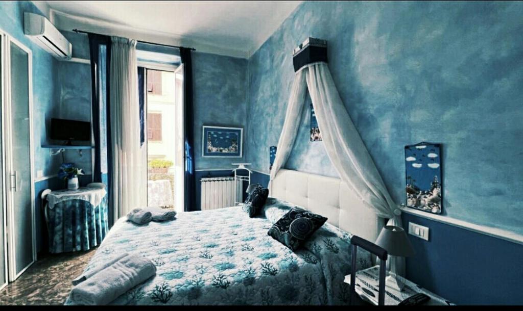 Dormitorio azul con cama y ventana en B&B Casa Celsi, en La Spezia