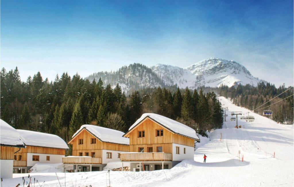 un lodge de ski dans la neige avec des montagnes en arrière-plan dans l'établissement Cozy Home In Altaussee With Sauna, à Altaussee