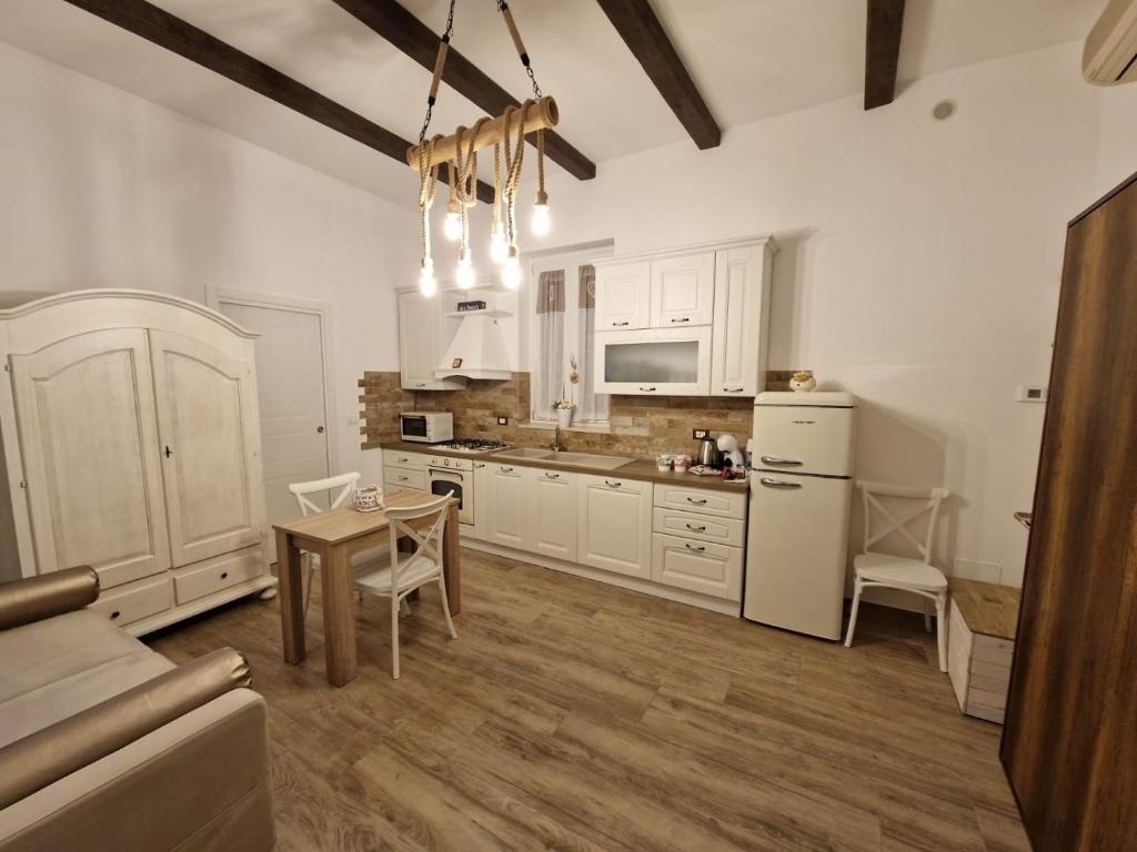 cocina con armarios blancos, mesa y sillas en Giù da nonna, en Lucera