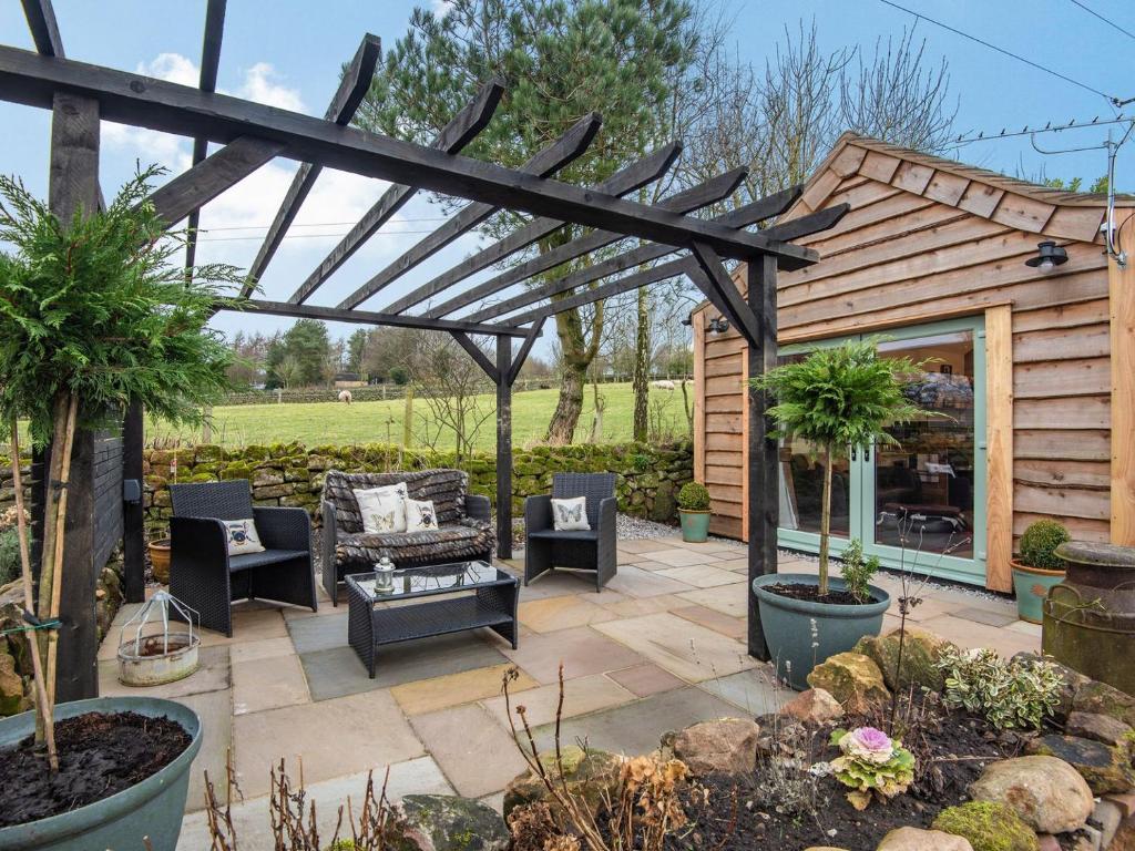 a patio with a wooden pergola and furniture at Little Pines Lodge in Rushton Spencer