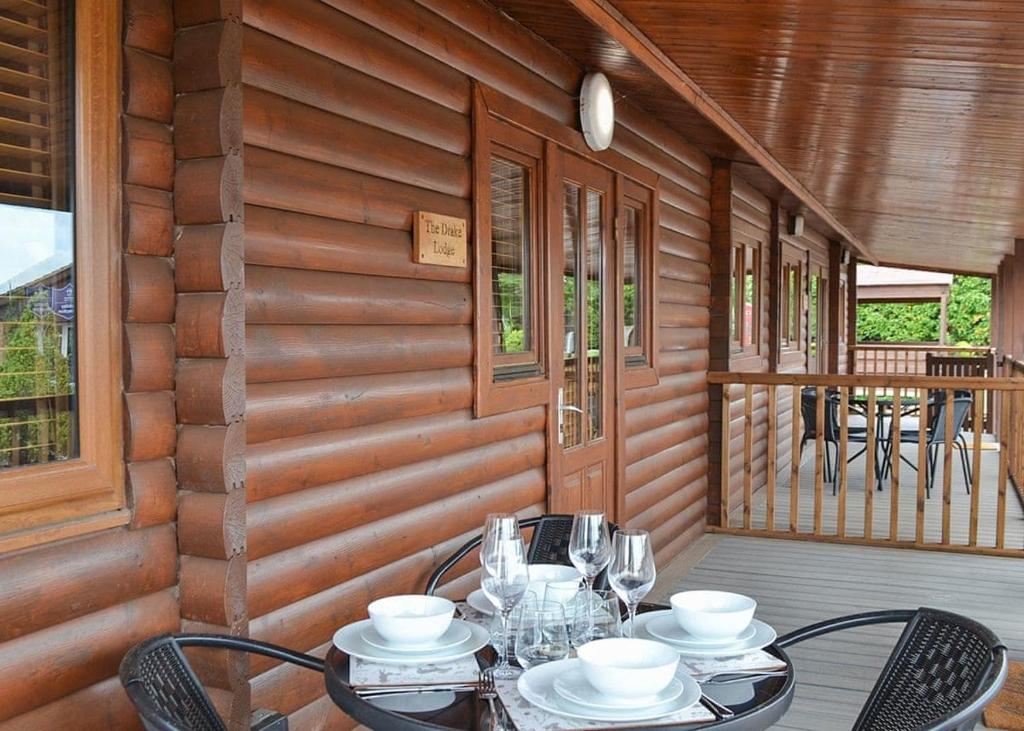 a table and chairs on the porch of a cabin at Bosworth Lakeside Lodges 