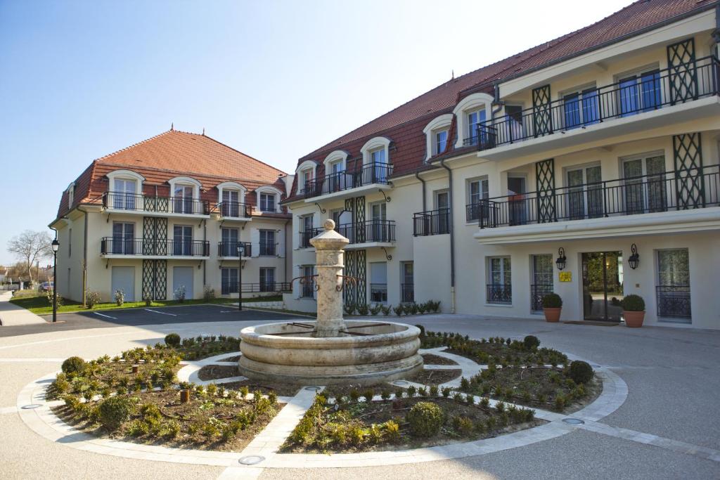 a fountain in a courtyard in front of a building at Medicis Home Beaune in Beaune