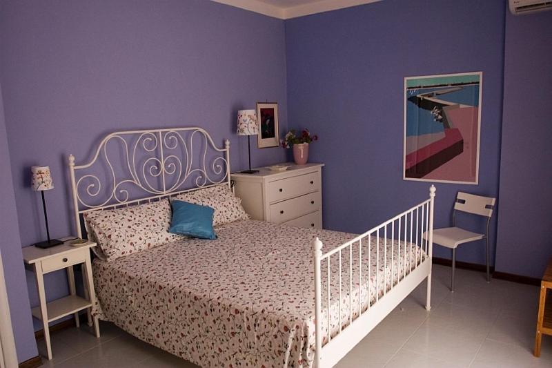 a bedroom with a white bed and a purple wall at Camere In Centro in Agropoli