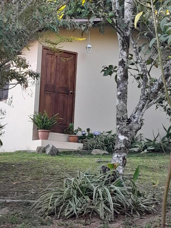 ein Haus mit einer Holztür und einem Baum in der Unterkunft Cabaña El Cielo de María in Boquete
