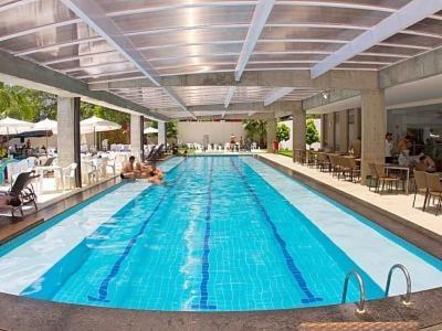 a large swimming pool with blue water in a building at Apartamento Le Jardin - Suítes para Temporada in Caldas Novas