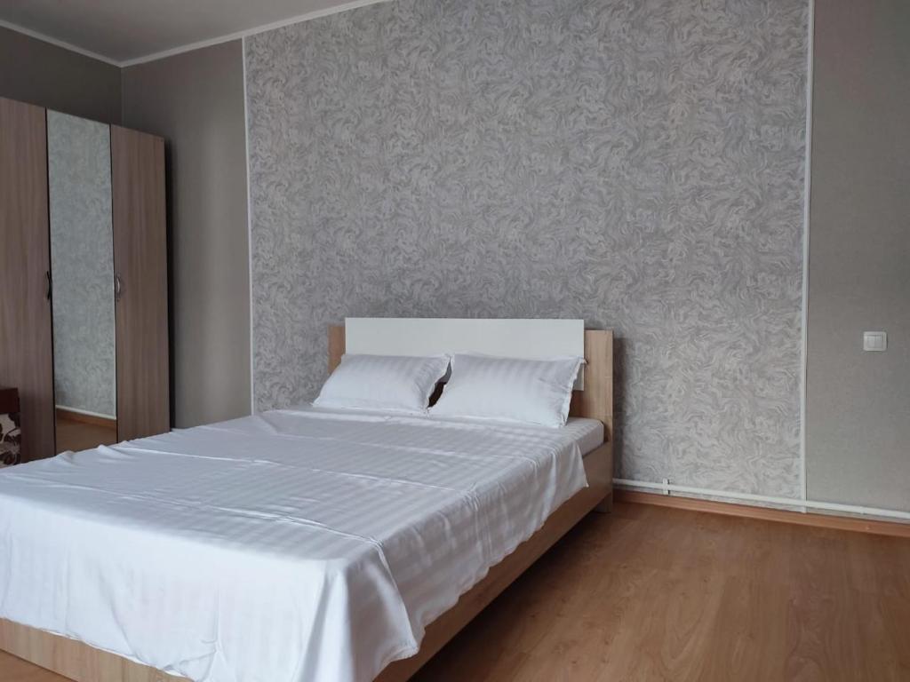 a bedroom with a large bed with white sheets at Апартаменты Жаяу Мусы 7А in Pavlodar