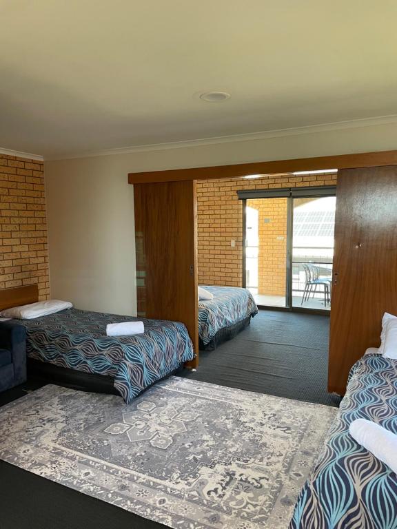a hotel room with two beds and a balcony at Lake Mulwala Hotel in Mulwala