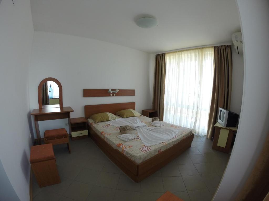 1 dormitorio con cama, mesa y espejo en Hotel Filland en Sozopol