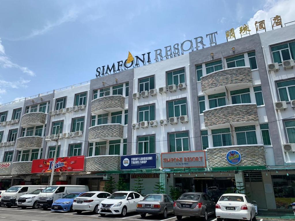 Simfoni Resort Langkawi في كواه: مبنى كبير فيه سيارات تقف امامه