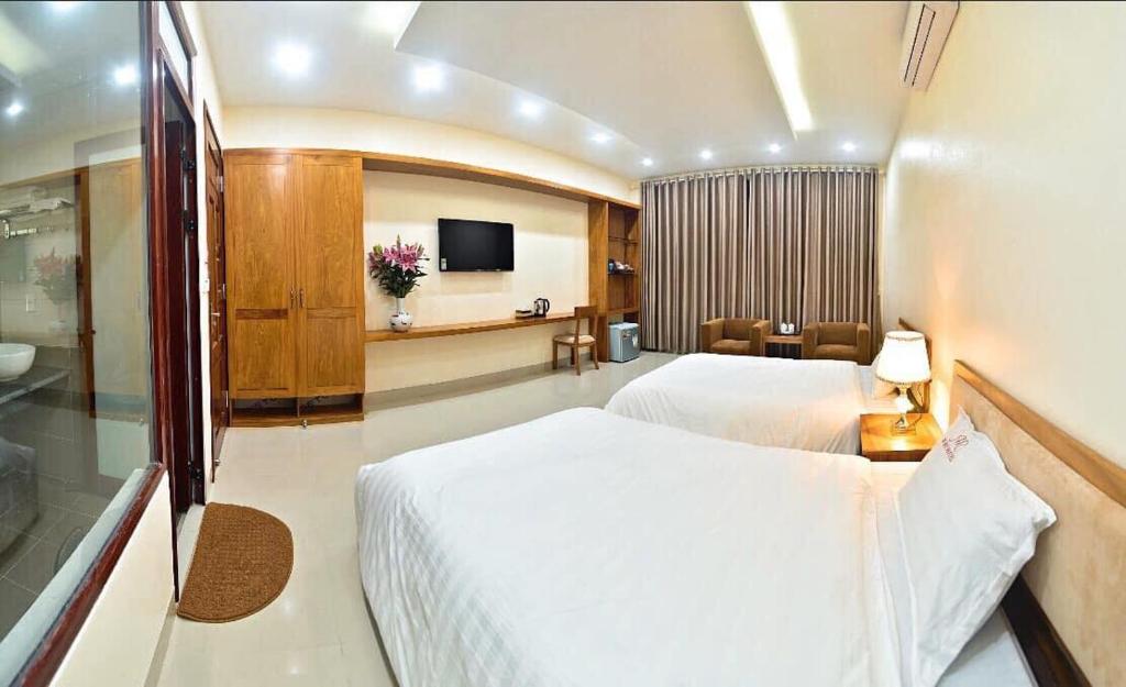 Nam ÐịnhにあるRuby Hotelのベッドとテレビが備わるホテルルームです。