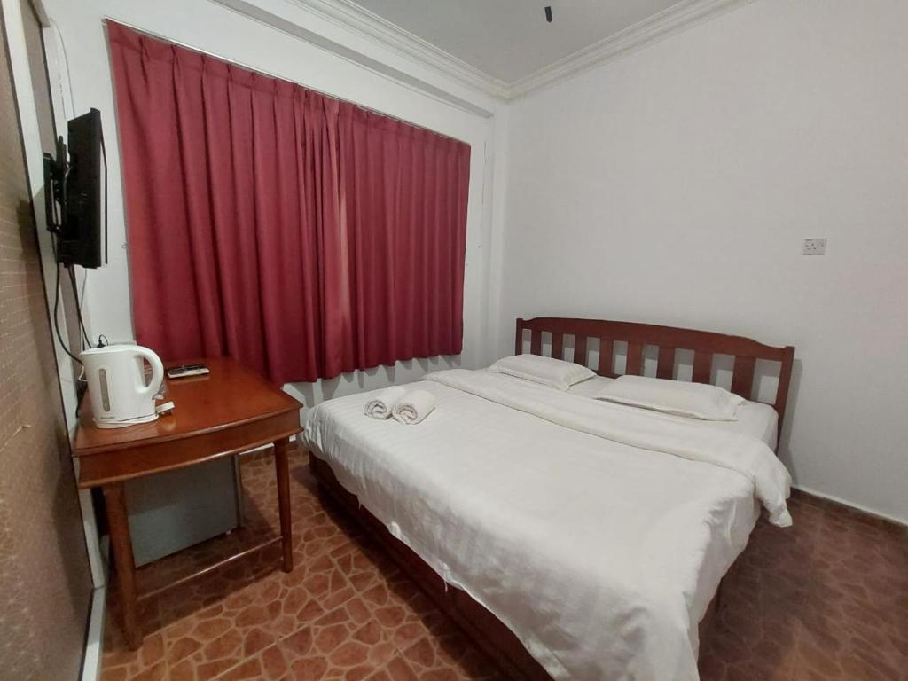 1 dormitorio con cama con cortina roja y mesa en Warisan Family inn @ Seafront, en Semporna