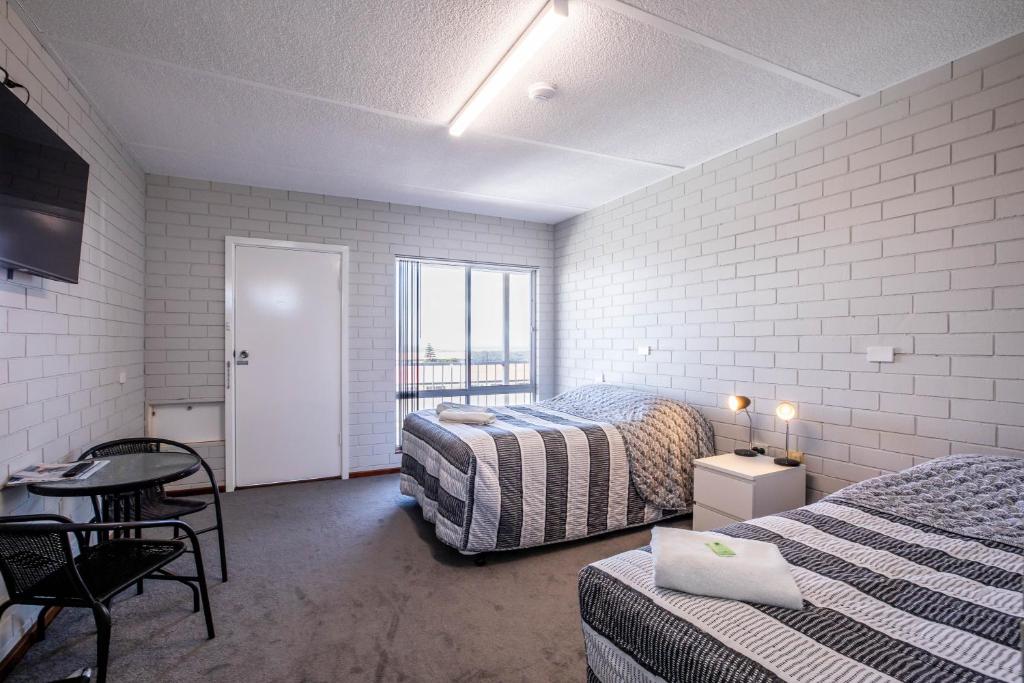 a bedroom with two beds and a table and chairs at Augusta Hotel Motel in Augusta