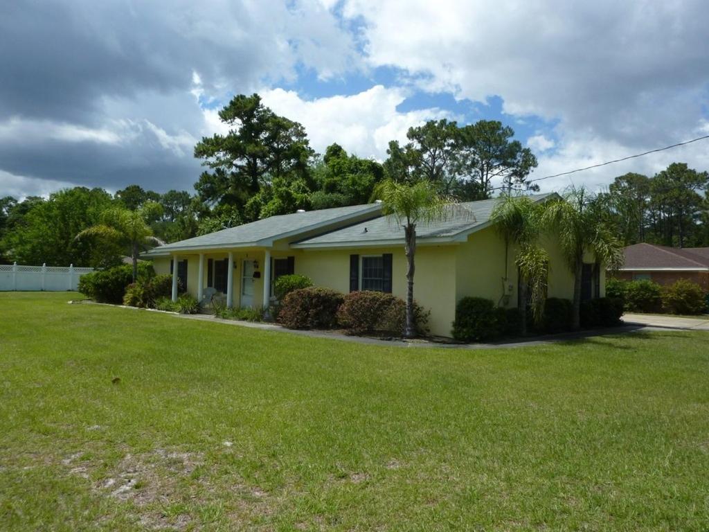 a small yellow house with a green yard at LYONS DEN - 3 Bedroom Home home in Jekyll Island