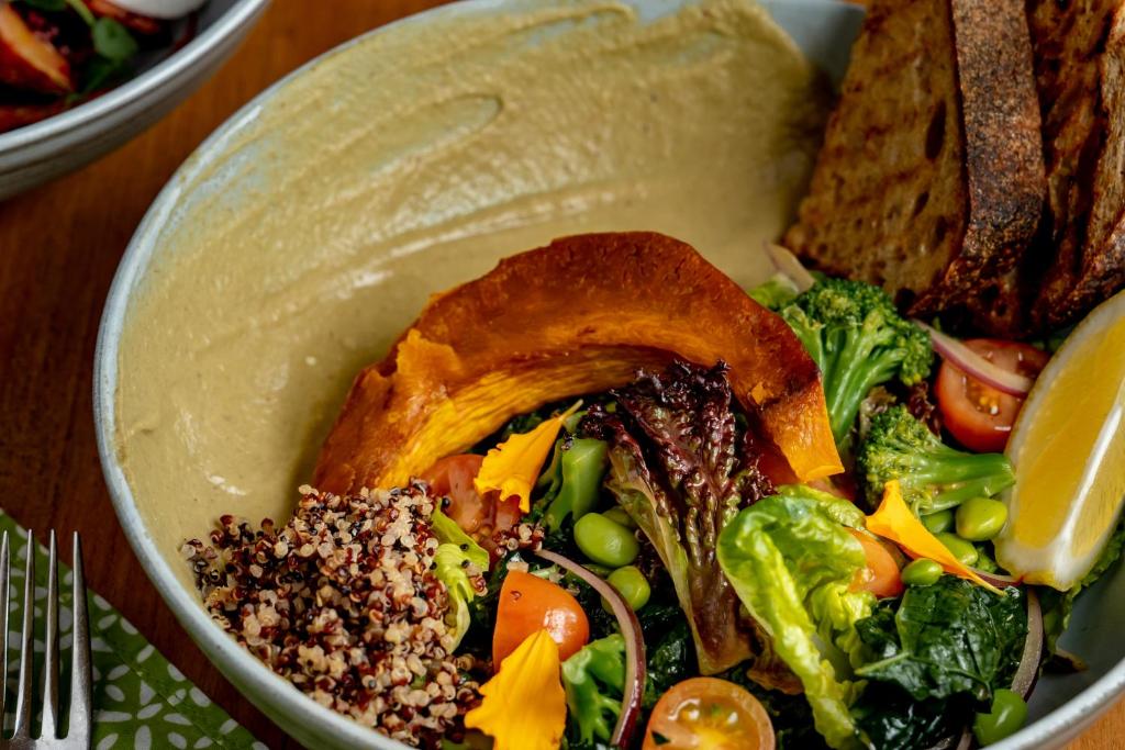 a bowl of salad with bread and vegetables on a table at Jati Cottage in Ubud