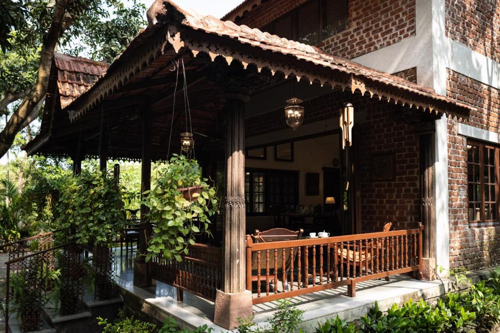 a porch of a brick house with a bench at amã Stays & Trails Asanji Wadi, Alibag in Alibaug