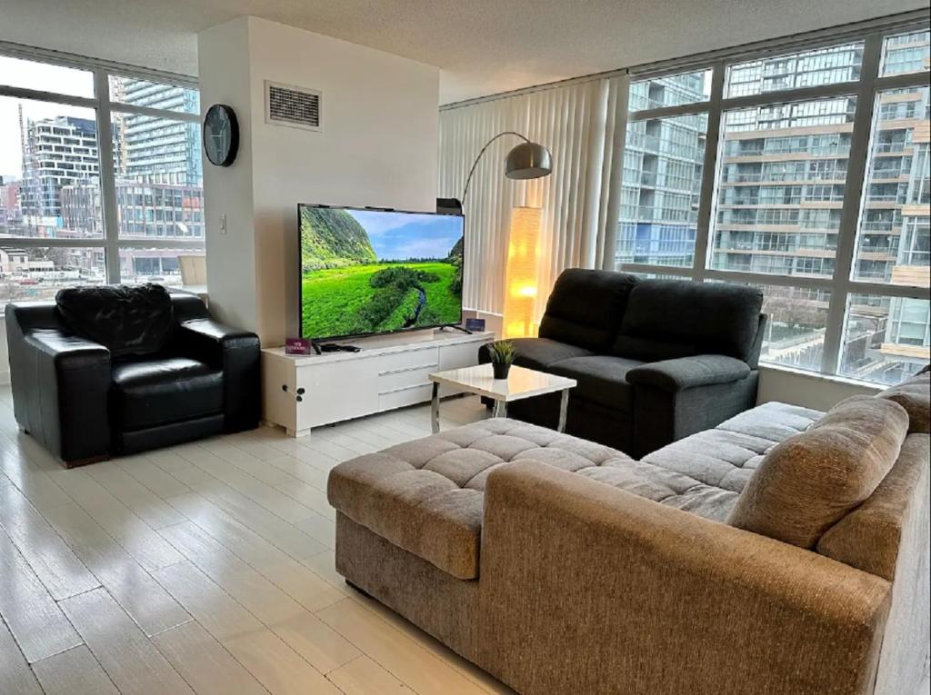 a living room with a couch and a flat screen tv at 1200+sqft Luxury Corner Suite in Toronto