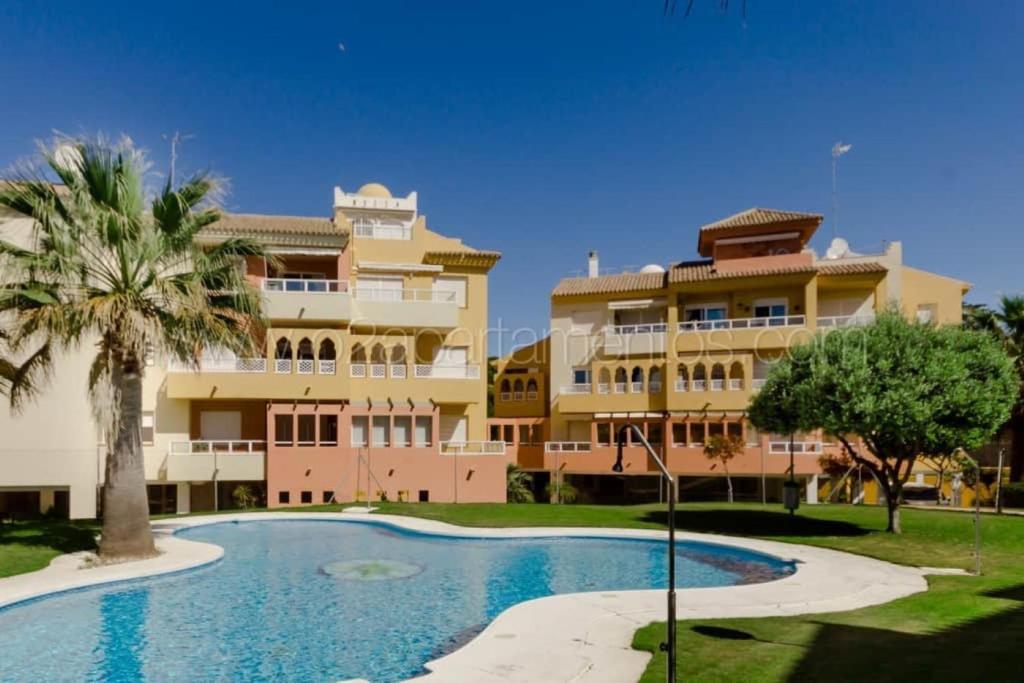 un edificio con piscina di fronte a un edificio di La Alcazaba de Cristina a El Puerto de Santa María