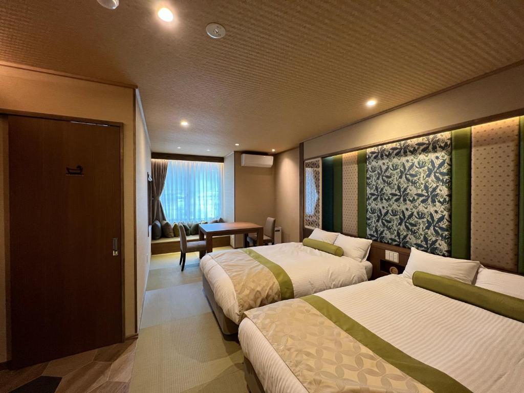 Habitación de hotel con 2 camas y mesa en Marukyoo, en Nikko
