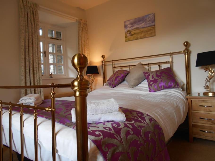 1 dormitorio con 1 cama grande con almohadas moradas en The Granary, Old Corn Mill, Yorkshire Dales, en West Burton