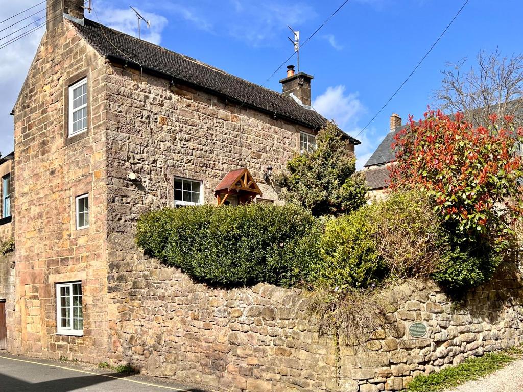 an old stone building with bushes on the side of it at Gate Cottage in Matlock