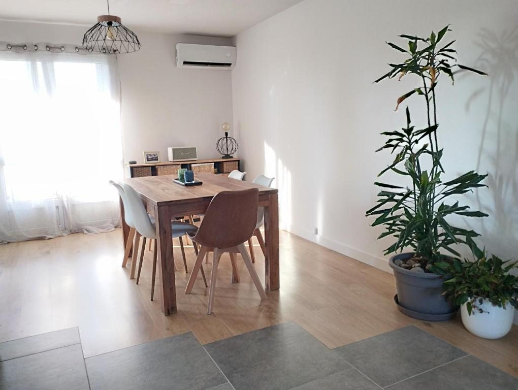 ein Esszimmer mit einem Holztisch und Pflanzen in der Unterkunft Appartement cosy proche mer in La Seyne-sur-Mer