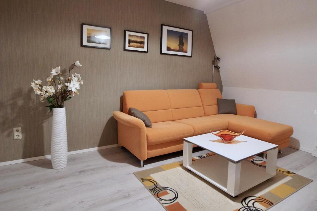 a living room with an orange couch and a table at Ferienwohnung Ostard 2 in Thale